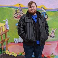 photo of Kyle in front of a mural